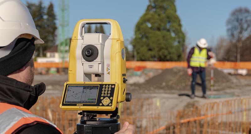 Leica iCON manual construction total station used by two construction workers on construction site